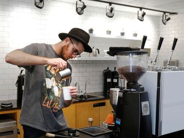 Beau Maddox pours steam milk to make a cup of Latte at Hands + Rose Coffee, located inside...