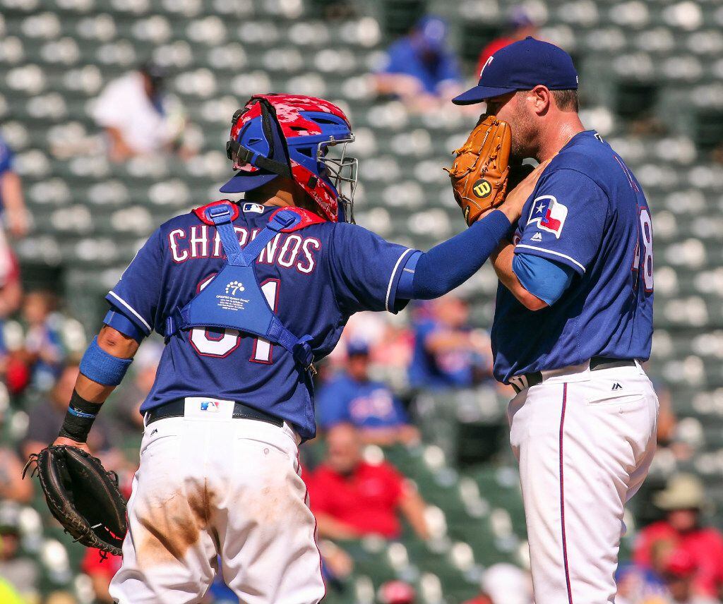 Texas Rangers catcher Robinson Chirinos (61) visits starting pitcher Colby Lewis (48) at the...