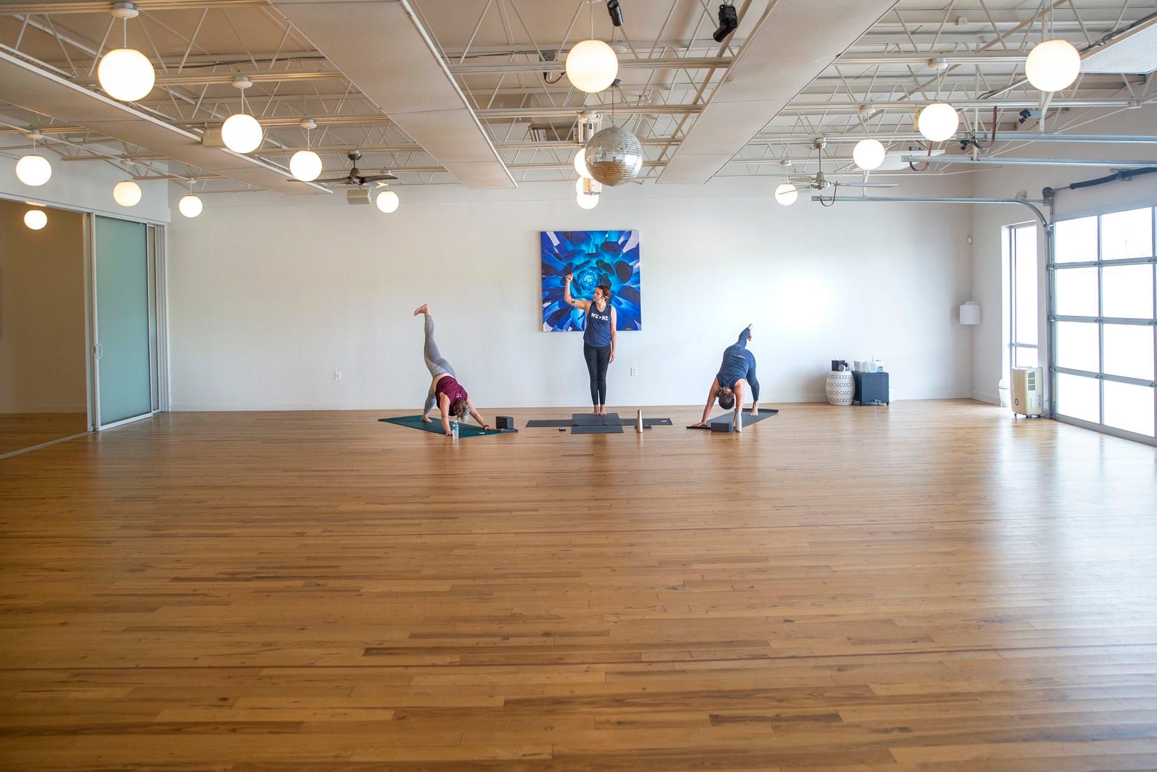 Certified yoga instructor Alli Carpenter (center) looks up to a digital video camera to address students attending an online all-levels Baptiste yoga flow class in which instructors Valary Bobb (left) and Kila Rennaker demonstrate poses at the Indigo Yoga studio in Fort Worth, Texas, on Wednesday, March 18, 2020. The studio transferred their classes to an online format in light of the COVID-19 pandemic precautions encouraging individuals to stay home. (Lynda M. Gonzalez/The Dallas Morning News)