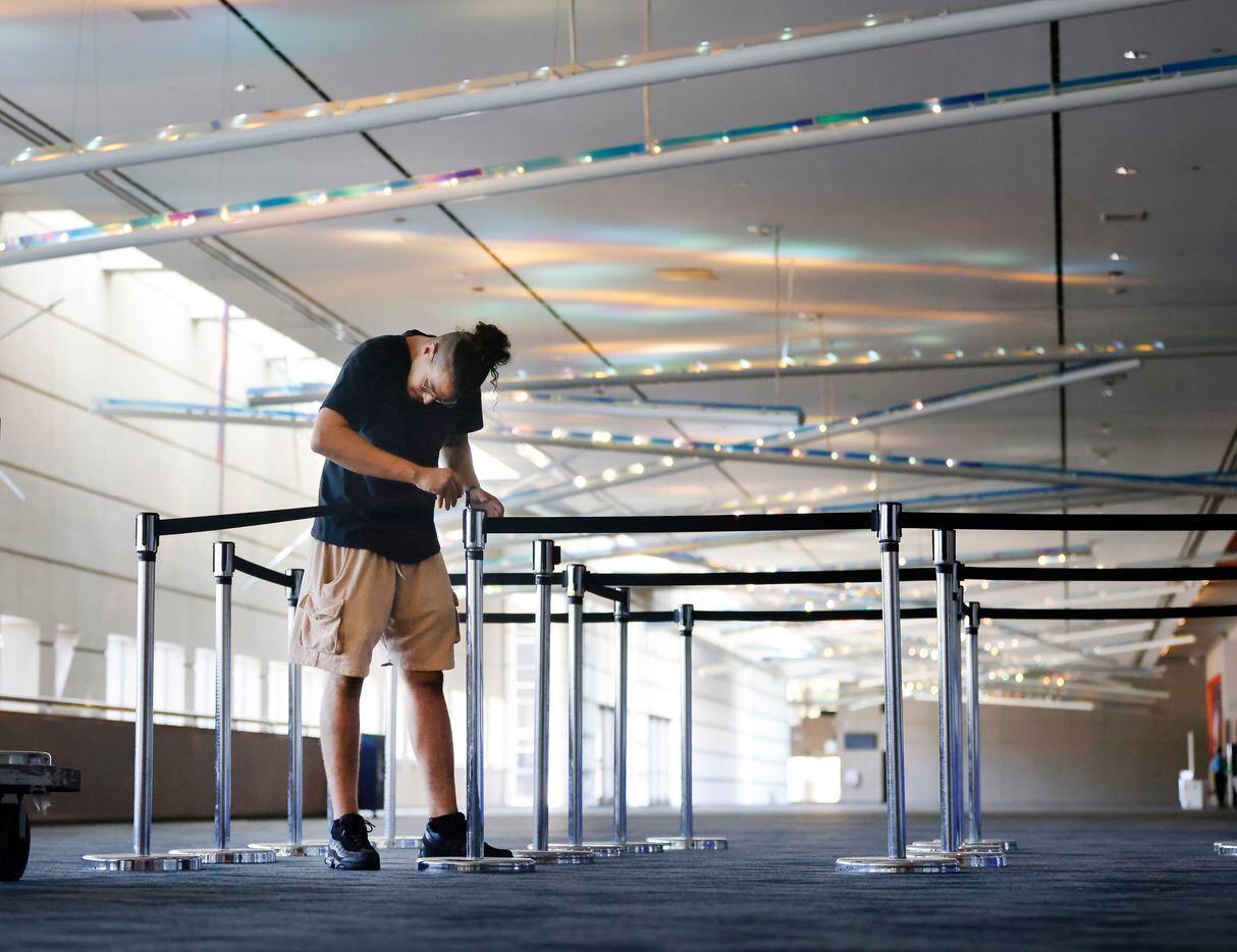 Decorator Dallas Sonnier of Freeman sets up stanchions outside the exhibit halls as a crews...