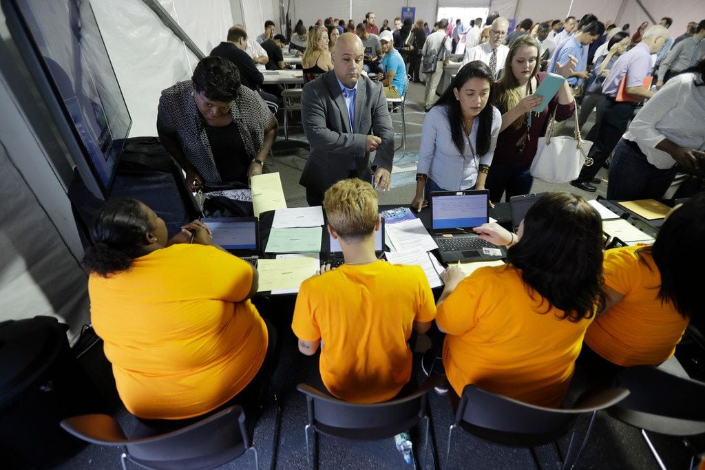In this Wednesday, Aug. 2, 2017, file photo, job candidatessign in for a job fair at the...