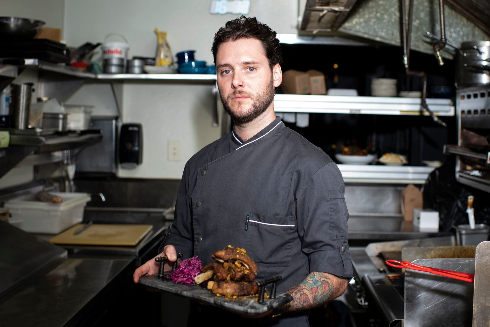 Chef Marshall Cole holds the Apple Glazed Pork Ribs inside the kitchen at The Mitchell in downtown Dallas.