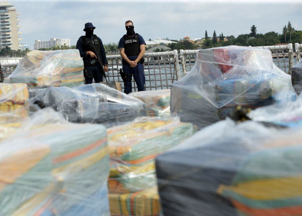 Coast Guardsmen stand over pallets containing more than 26 tons of cocaine worth at least...