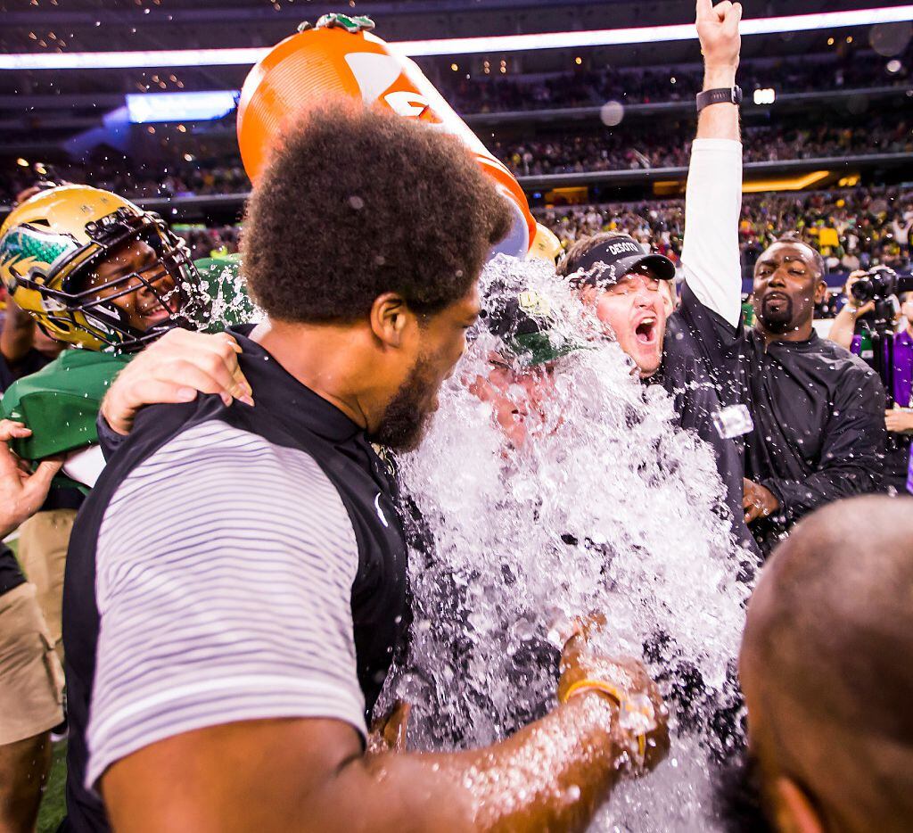 DeSoto head coach Todd Peterman is doused with water by his players after a victory over...