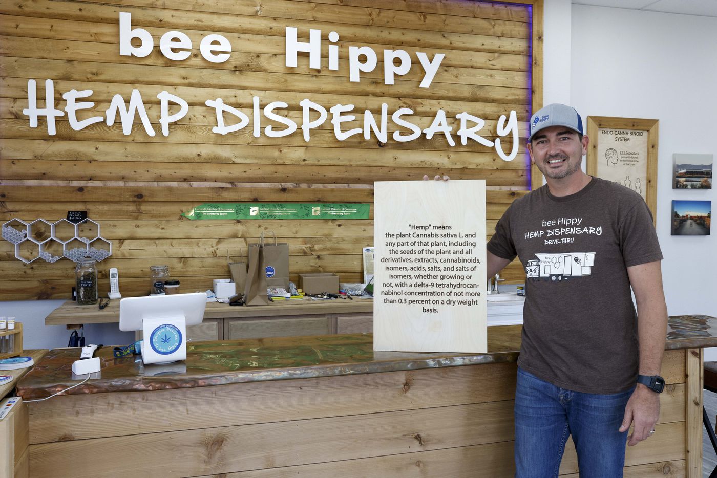 Bee Hippy Hemp Dispensary owner Chris Fagan holds up a poster-sized definition of hemp that...