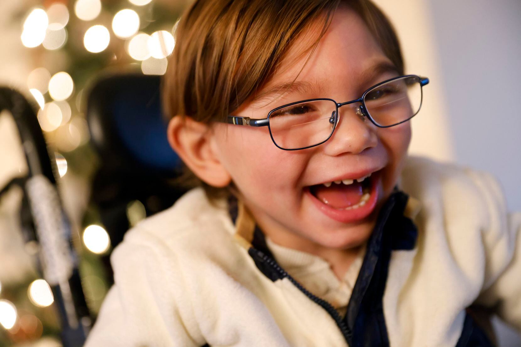 Sutton, who uses a wheelchair because of his cerebral palsy, laughs with his mother,...