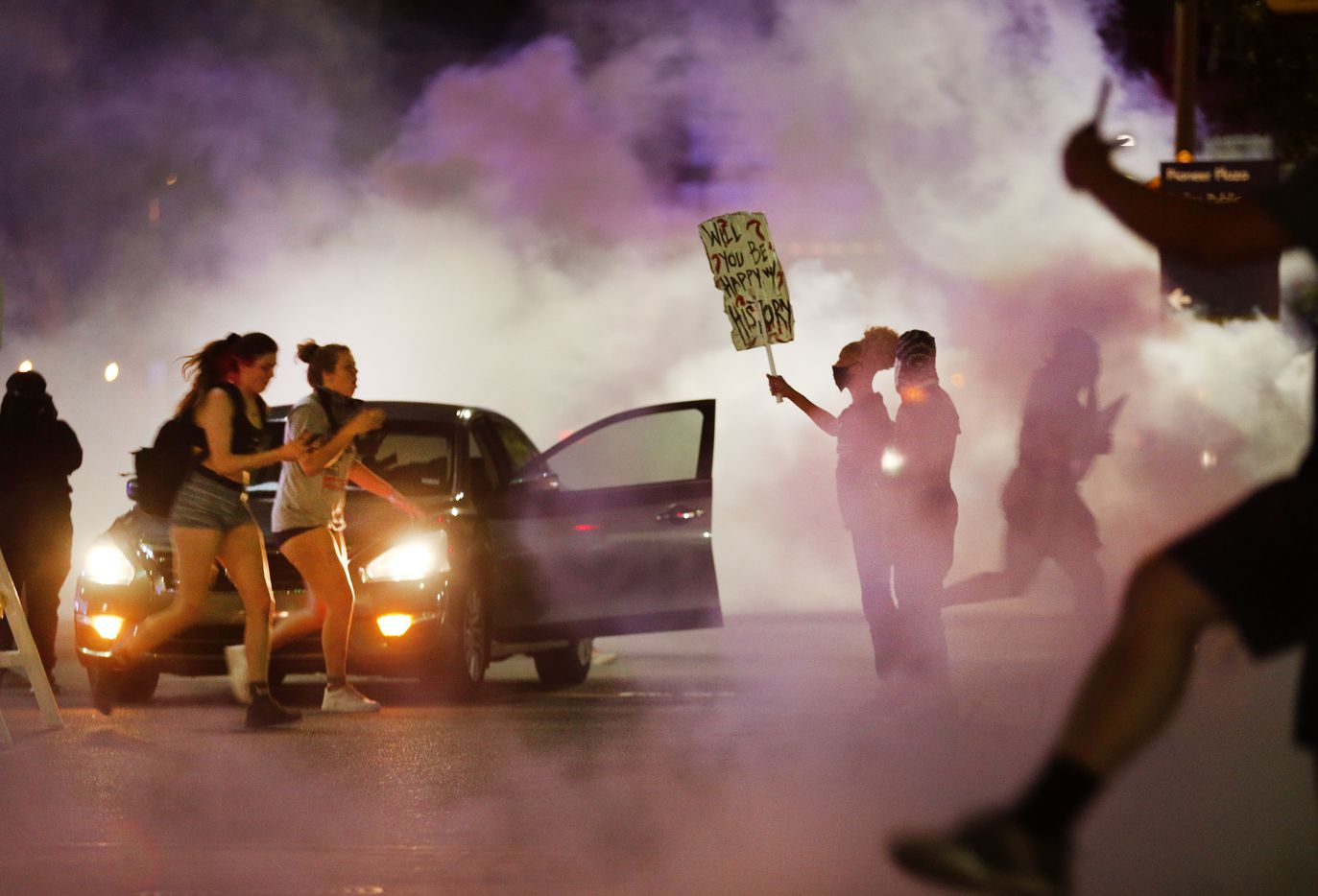 A pair of protestors are overcome with tear gas as they run from Dallas Police tactical...