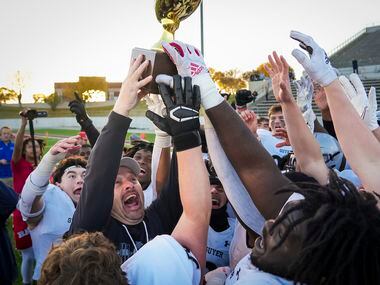 Denton Guyer head coach Reed Heim lifts the game trophy as he celebrates with his players...