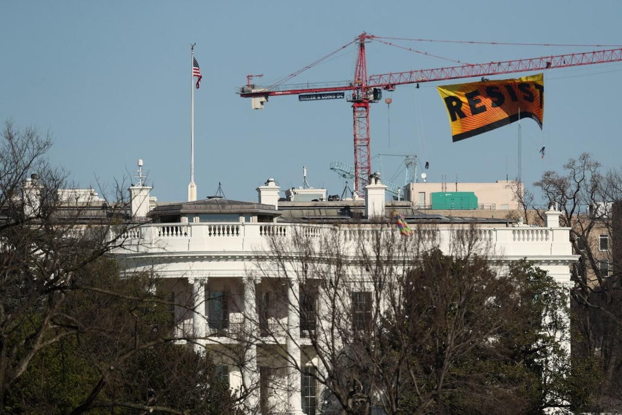 Unos manifestantes de Greenpeace despliegan un baner que dice “resiste” frente a la Casa...