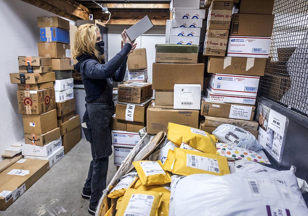 Managing a huge amount of packages, Diana Naramore, owner of Sip and Ship in Seattle, tidies a stack of boxes in the back of her store.