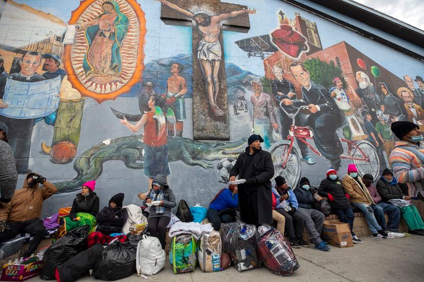 Migrantes comen y esperan ayuda, acampados en una calle del centro de El Paso, Texas, 18 de...