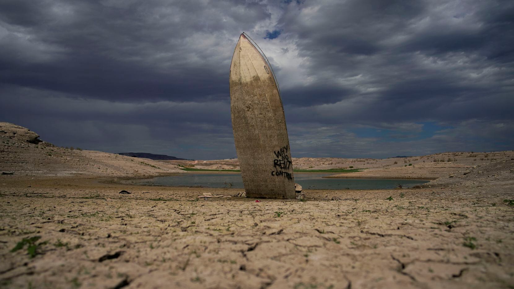 A formerly sunken boat sits upright with its stern stuck in the mud along the shoreline of...