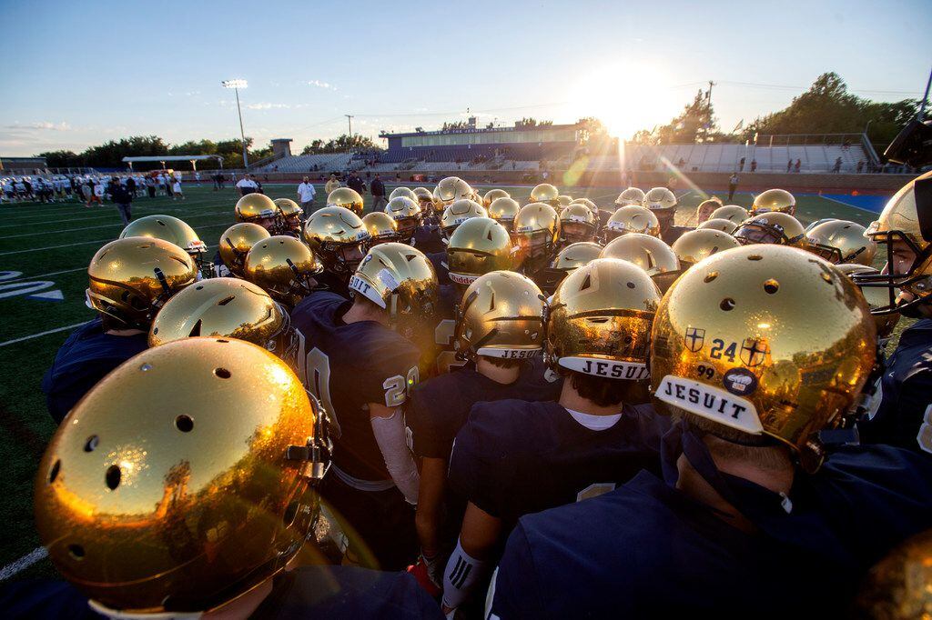 Jesuit players gather on the field during pregame warmups before a high school football game...