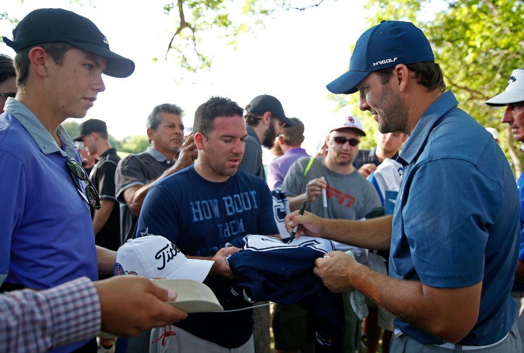 Former Dallas Cowboys quarterback Tony Romo (right) signs autographs for fans after playing...