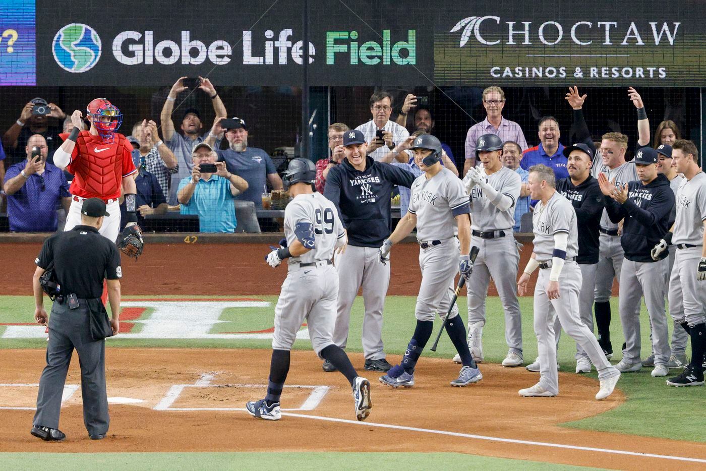 Members of the New York Yankees greet New York right fielder Aaron Judge (99) at home plate...
