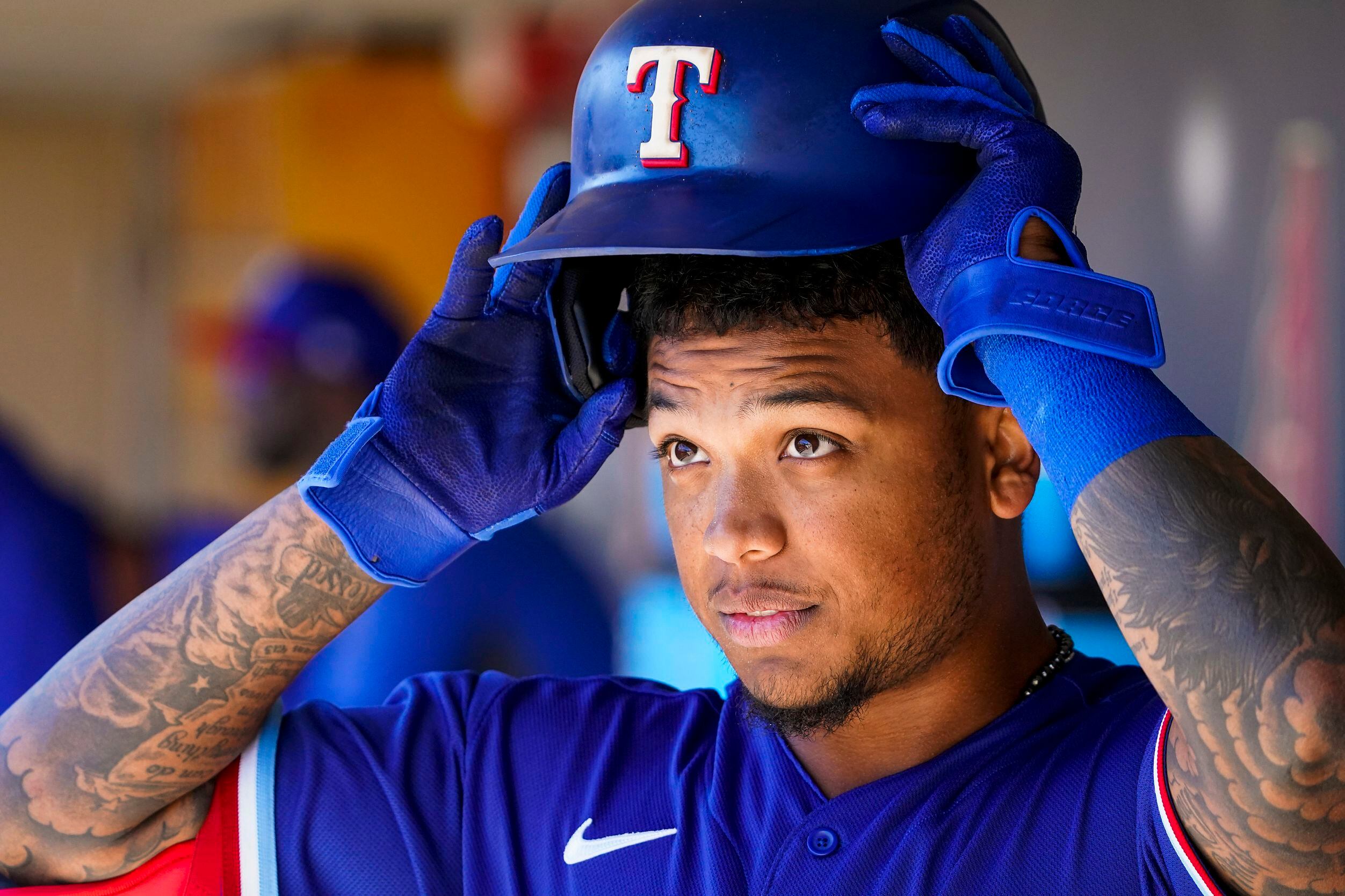 Texas Rangers outfielder Willie Calhoun puts on his batting helmet in the dugout before a...