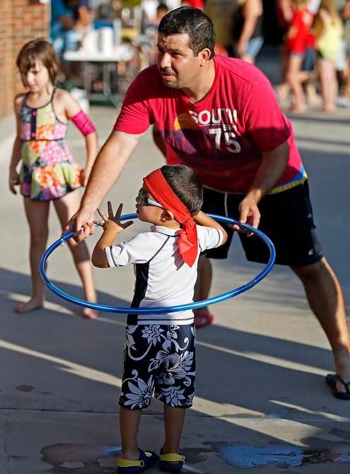
Oscar Hernandez of Plano helped his son Jaydin get set for a hula hoop contest at last...