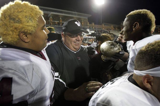 Wylie head coach Bill Howard celebrates with offensive lineman Brandon Dotson, on left, and...