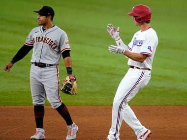 San Francisco Giants second baseman Donovan Solano, left, stands by the bag as Texas Rangers' Eli White celebrates his double in the sixth inning of a baseball game in Arlington, Texas, Wednesday, June 9, 2021. (AP Photo/Tony Gutierrez)