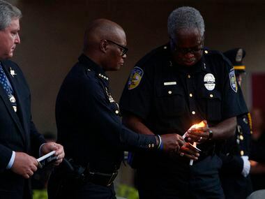 Dallas Police Chief David Brown (left) has his candle lit by DART police chief J.D. Spiller...