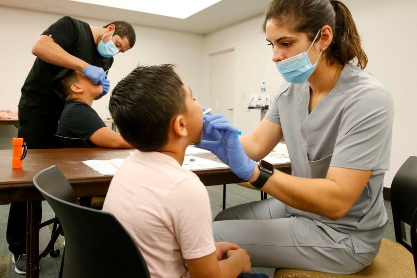 Roberto Rosales, de 12 años y su hermano Víctor, reciben revisiones dentales como parte de...