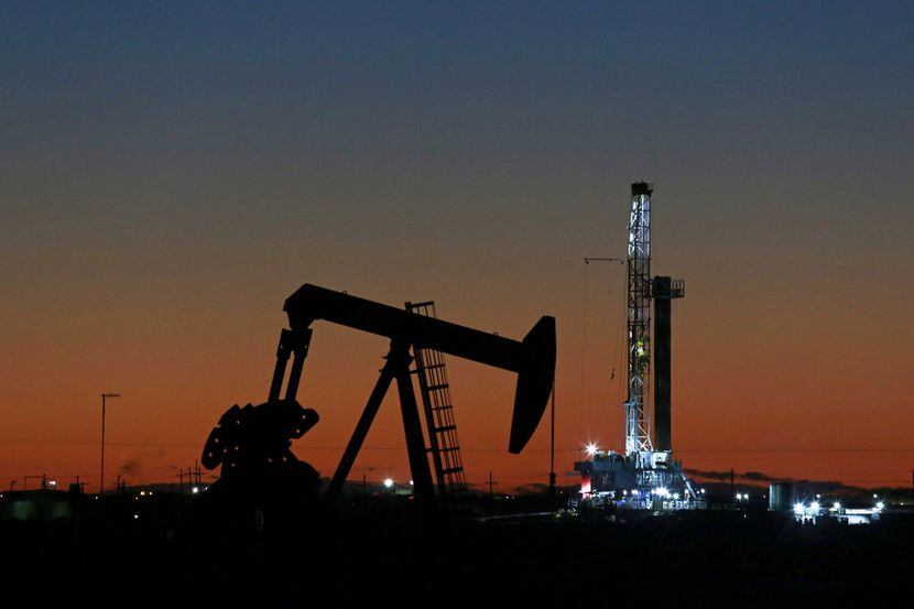In this Oct. 9, 2018, file photo, an oil rig and pump jack work along the roadside of FM...