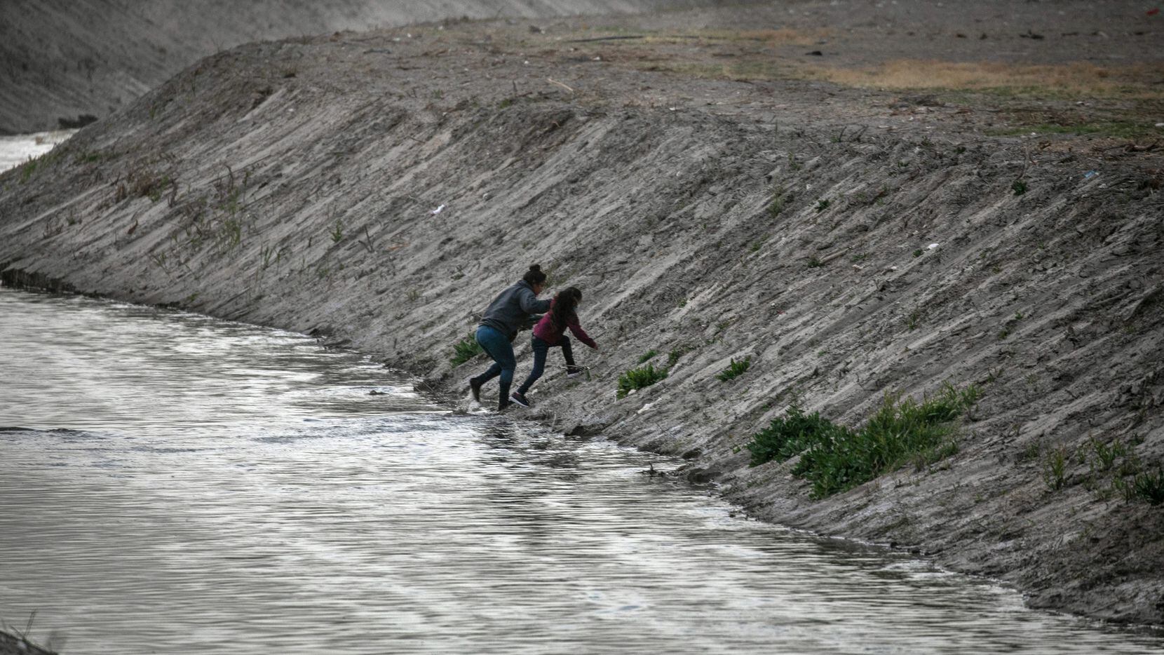 Asylum seekers scramble up the bank of the Rio Grande wafter crossing from Mexico into the...