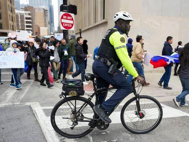 A Dallas police officer controls traffic as demonstrators march in opposition to Texas...