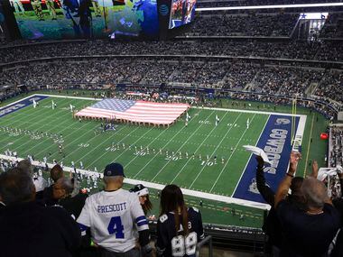 Dallas Cowboys fans stand in the stands as the national anthem is plays before an NFL game...