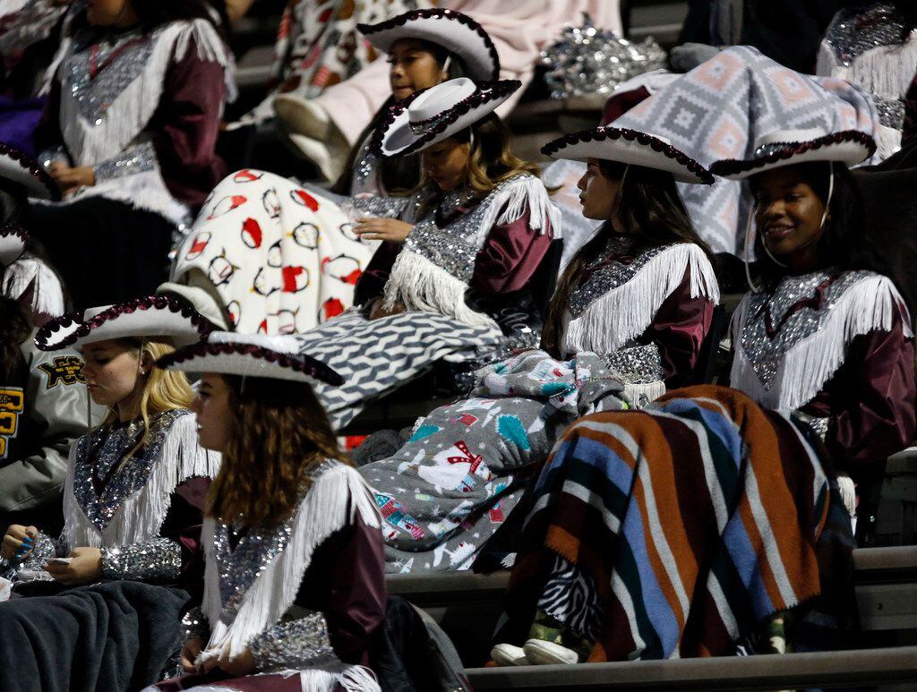 Mesquite drill team members sit under blankets to reduce the chill during the first half of...