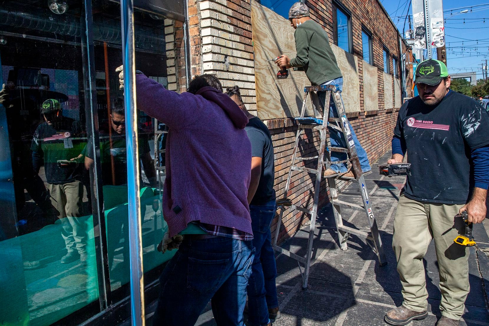 George Hernandez (right) and other employees at Tommy C Construction, LLC, board up the glass windows at Crowdus Bar in Deep Ellum in Dallas on Monday, Nov. 2, 2020. Businesses throughout Deep Ellum and downtown Dallas hired various contractors to board up their buildings to deter against possible looting that might occur after the general election. (Lynda M. González/The Dallas Morning News)