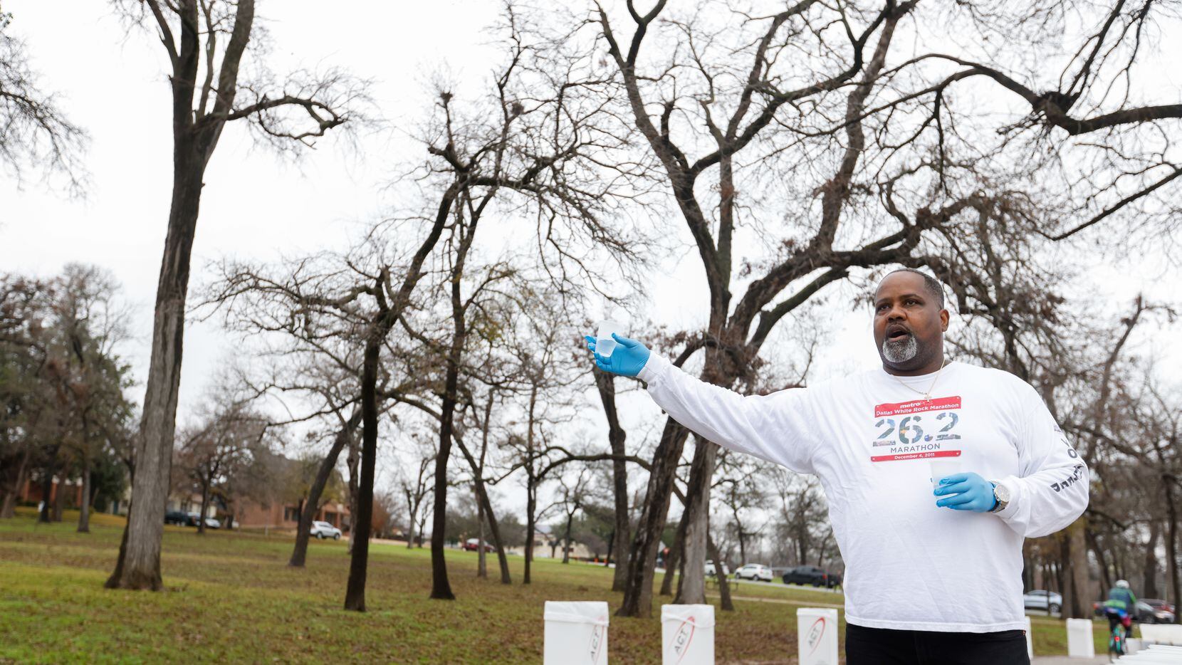 Cliff Piper yells to runners as he holds out water at the 17-mile mark of the BMW Dallas...