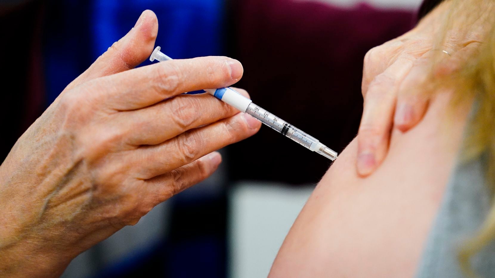 FILE - A health worker administers a dose of a COVID-19 vaccine during a vaccination clinic...