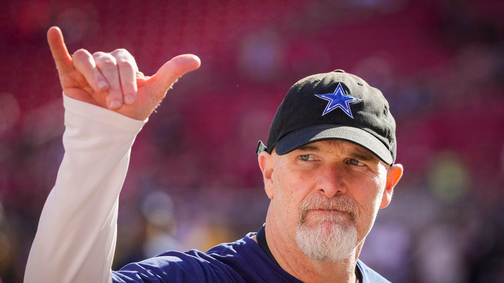 Dallas Cowboys defensive coordinator Dan Quinn motions to the crowd as the teams warm up...