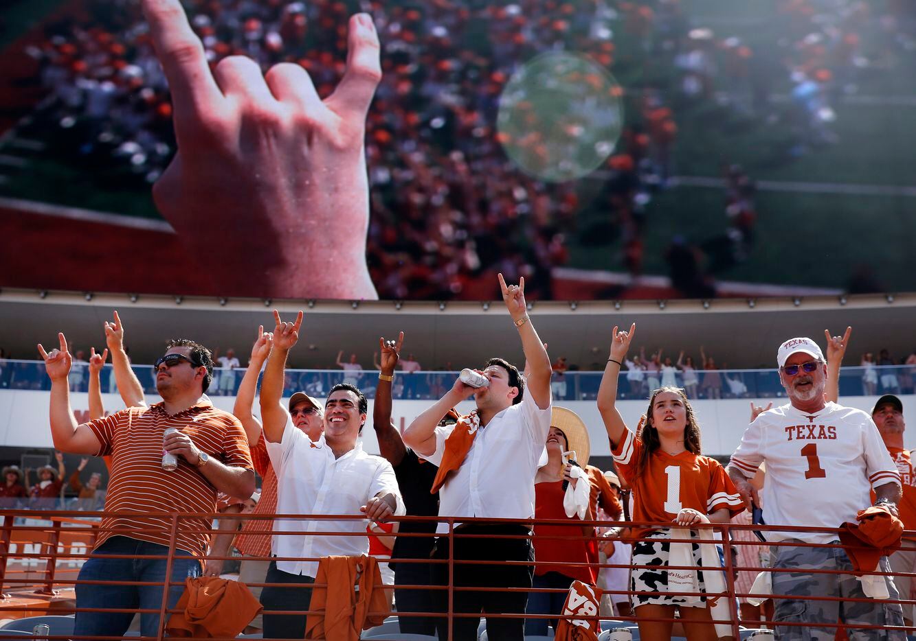 Texas Longhorns fans raises their hands with a ‘hook'em horns’ chant during their game...
