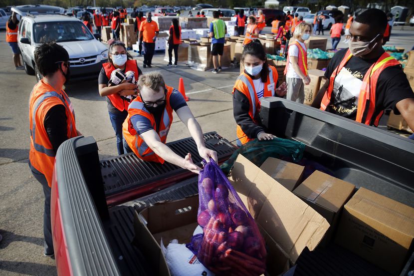 Un equipo de voluntarios carga vehículos con frutas y verduras en bolsas, cajas de productos...