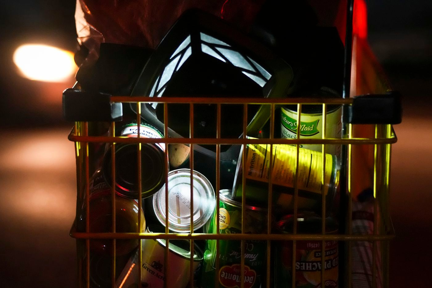 A woman experiencing homelessness pushes a cart filled with canned food in the 5400 block of...