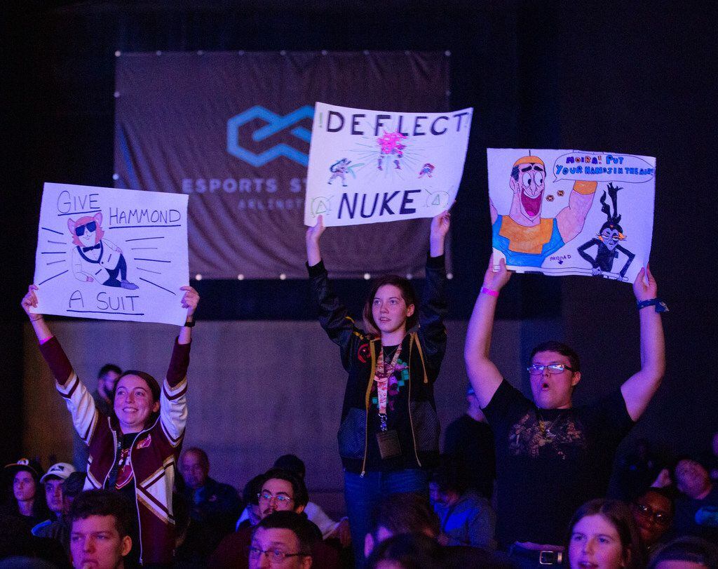 Fans hold signs during the season three opening weekend  match of the Overwatch League...