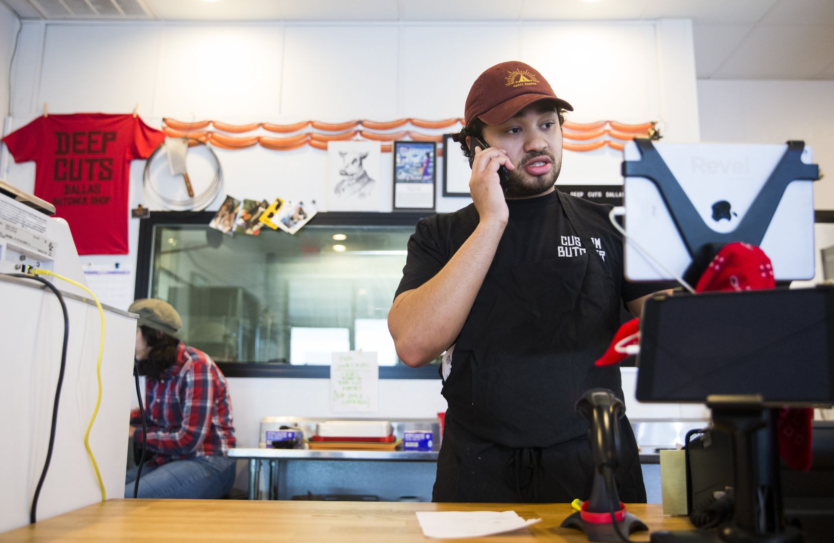 Isaiah Chavoya (right), of butcher shop Deep Cuts Dallas, takes a phone order on Sunday, March 22, 2020. Staffers ask for patience; the phone line is often busy.