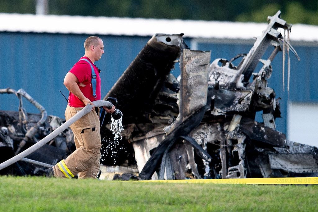 A firefighter carries a hose past wreckage of the plane in which Dale Earnhardt Jr., his wife and daughter were passengers, following a crash near Elizabethton Municipal Airport in Elizabethton, Tenn., Thursday, Aug. 15, 2019. Everyone on board survived the crash. (Calvin Mattheis/Knoxville News Sentinel via AP)
