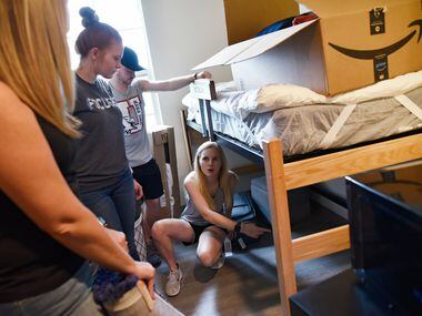 Freshman Makinley Eddlemon (right), 18,  coordinates move in and storage in her dorm room...