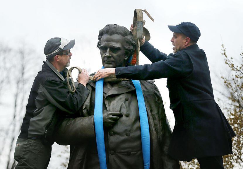 Parks Department workers place a harness over a statue of J. Marion Sims, a surgeon...