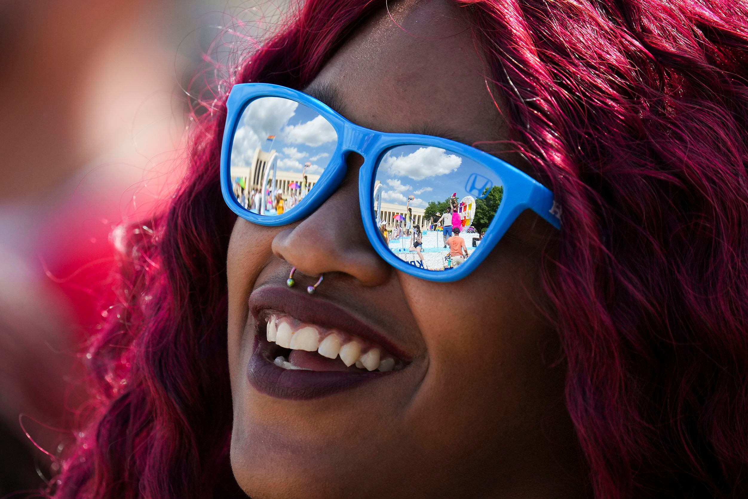 Participants and floats are reflected in the sunglasses of Dezah Hubbard as they march...