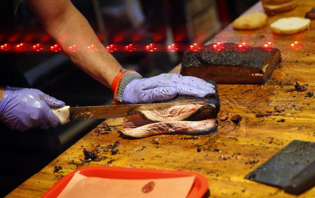 Owners Todd David cut slices from a brisket at the newly reopened Cattleack Barbeque,...