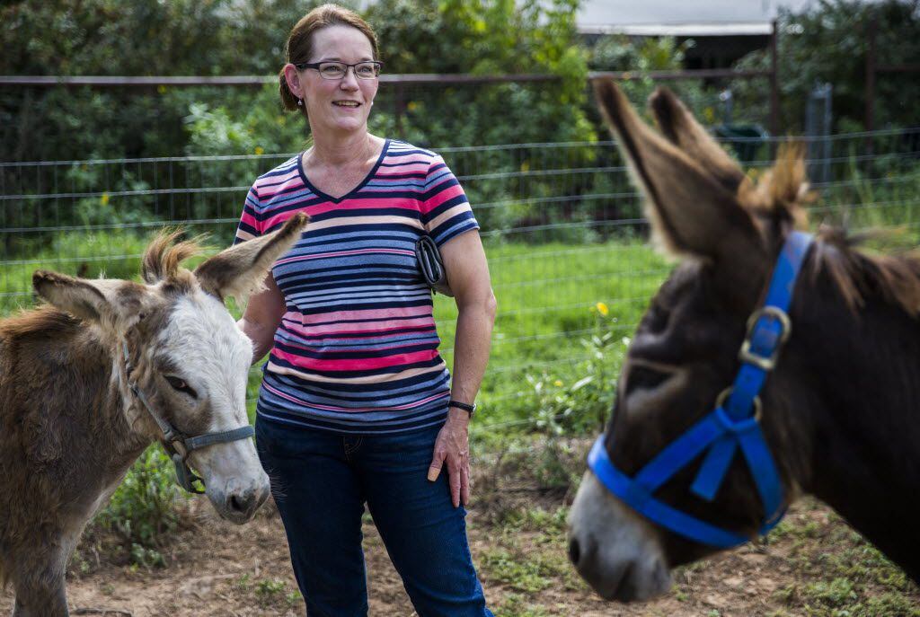 Elizabeth Hendel of Royce City, Texas stands between donkeys Ethel and Charlie.