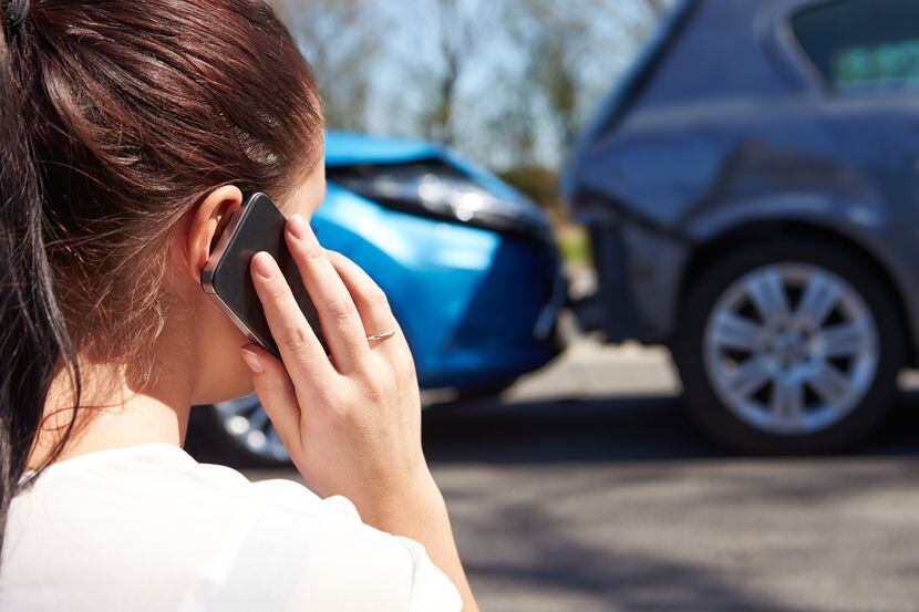 Female Driver Making Phone Call After Traffic Accident, looking at the accident