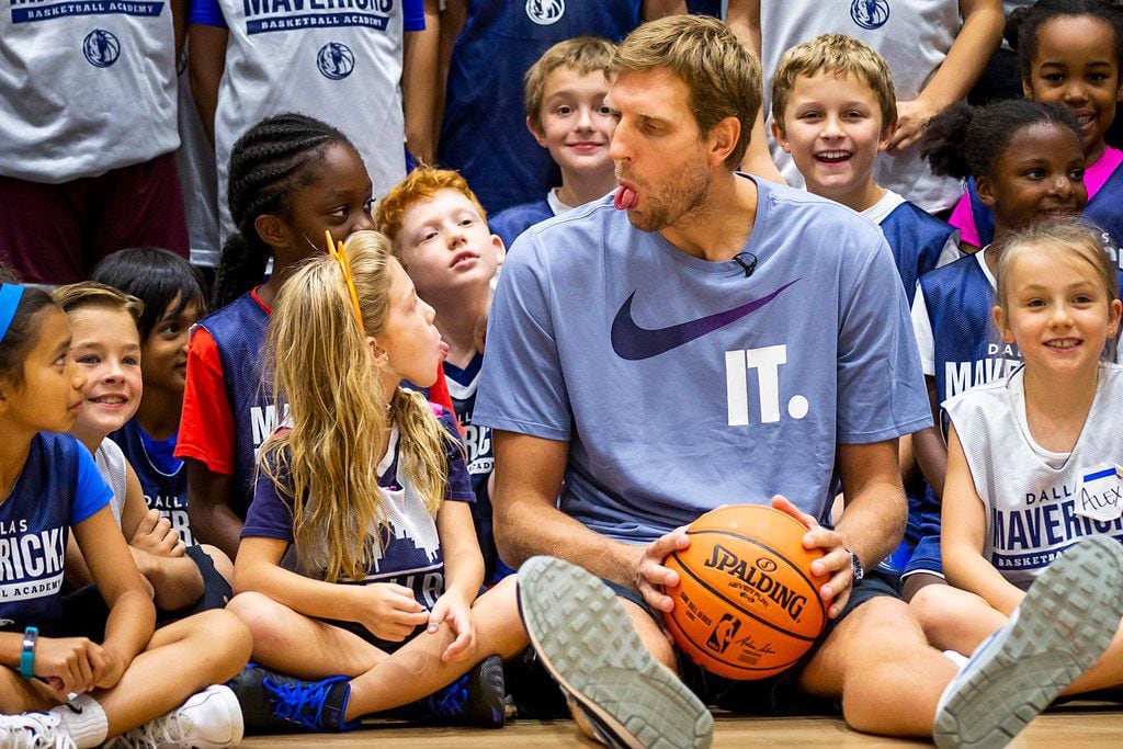 Dirk Nowitzki of the Dallas Mavericks sticks his tongue out with Amelie Schiavon, 8, (left) while sitting down with kids before taking a group photo with participants in the Mavericks Summer Hoop Camp at the Collin College Spring Creek Campus on Wednesday, Aug. 8, 2018, in Plano. (Smiley N. Pool/The Dallas Morning News)