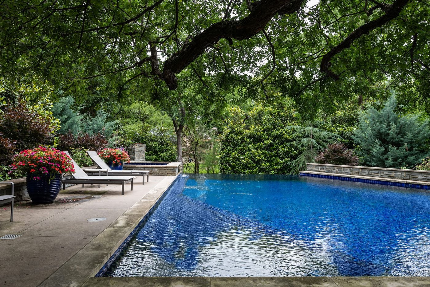 The terraced backyard at 9024 Broken Arrow Lane allows for multiple outdoor entertaining areas. There is also an infinity-edge pool that flows into a water feature.