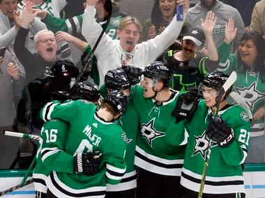 Dallas Stars center Roope Hintz (second from right) is congratulated by teammates and fans...