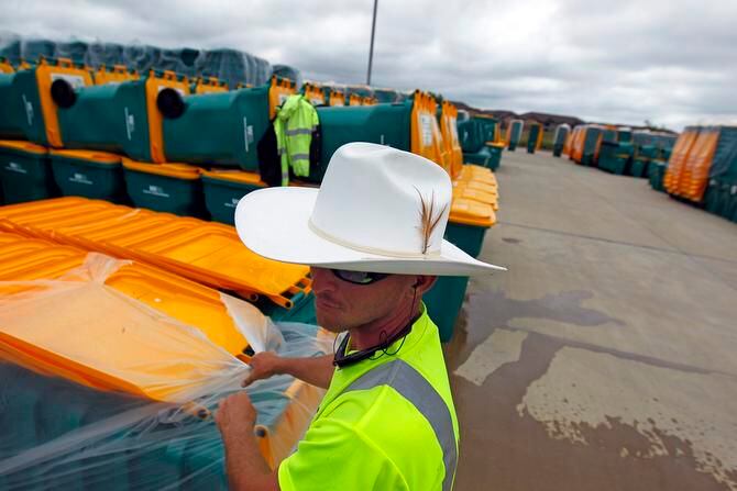 
WasteRec worker David May unwraps new trash carts in Lewisville. As part of its switch to...
